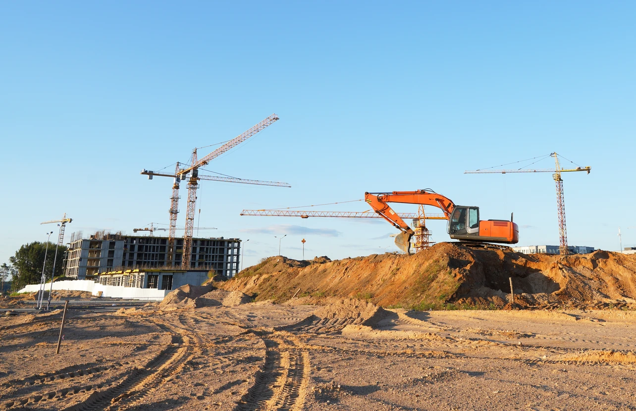 Chantier de terrassement en extérieur avec bulldozer jaune sur terrain aride sous ciel nuageux au coucher du soleil