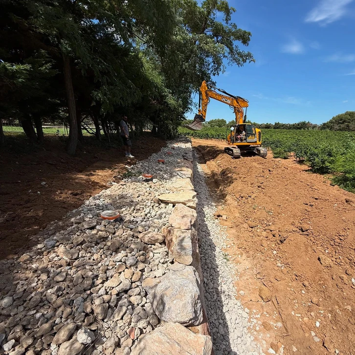 Chantier extérieur de construction d'un mur de soutènement en blocs de béton (parpaings), avec renforts verticaux en acier dépassant en tête