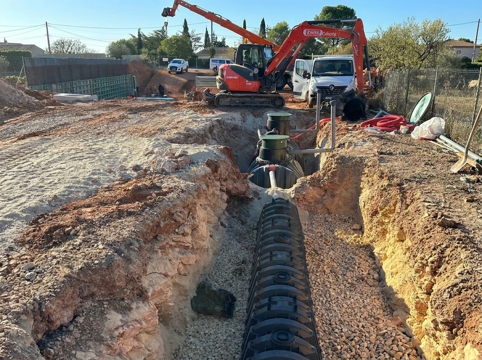 Chantier de terrassement en extérieur avec pelleteuse hydraulique orange chargeant de la terre dans un camion-benne rouge